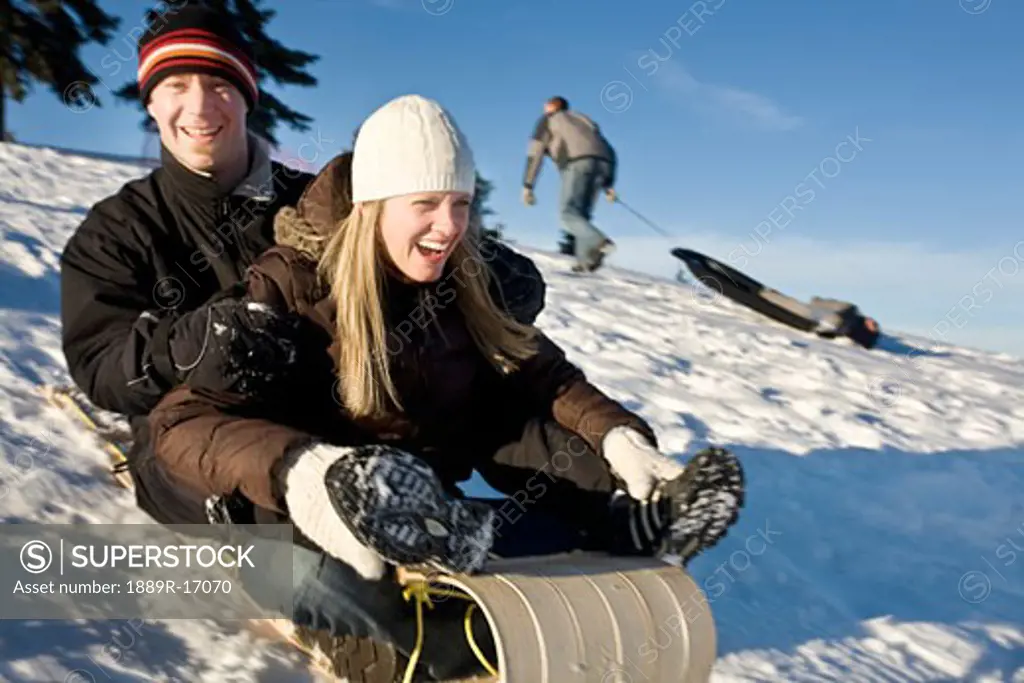 Winter sports; Couple tobogganing down a hill