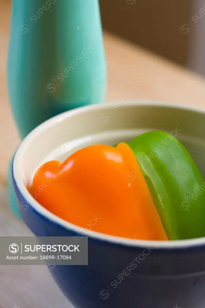 Peppers in a bowl; Orange and green pepper in a bowl