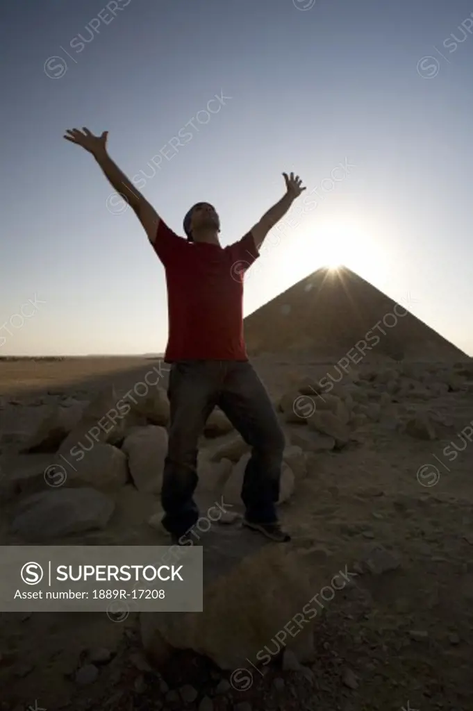Dahshur, Egypt; Man with arms raised in front of the Red Pyramid