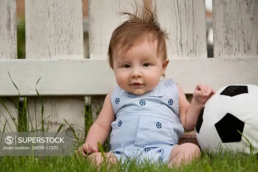 Baby boy; baby boy sitting in the grass with a soccer ball
