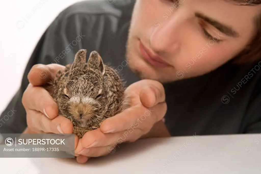 Young man holding a baby rabbit