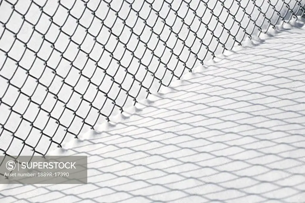 Chain link fence and shadow in snow  
