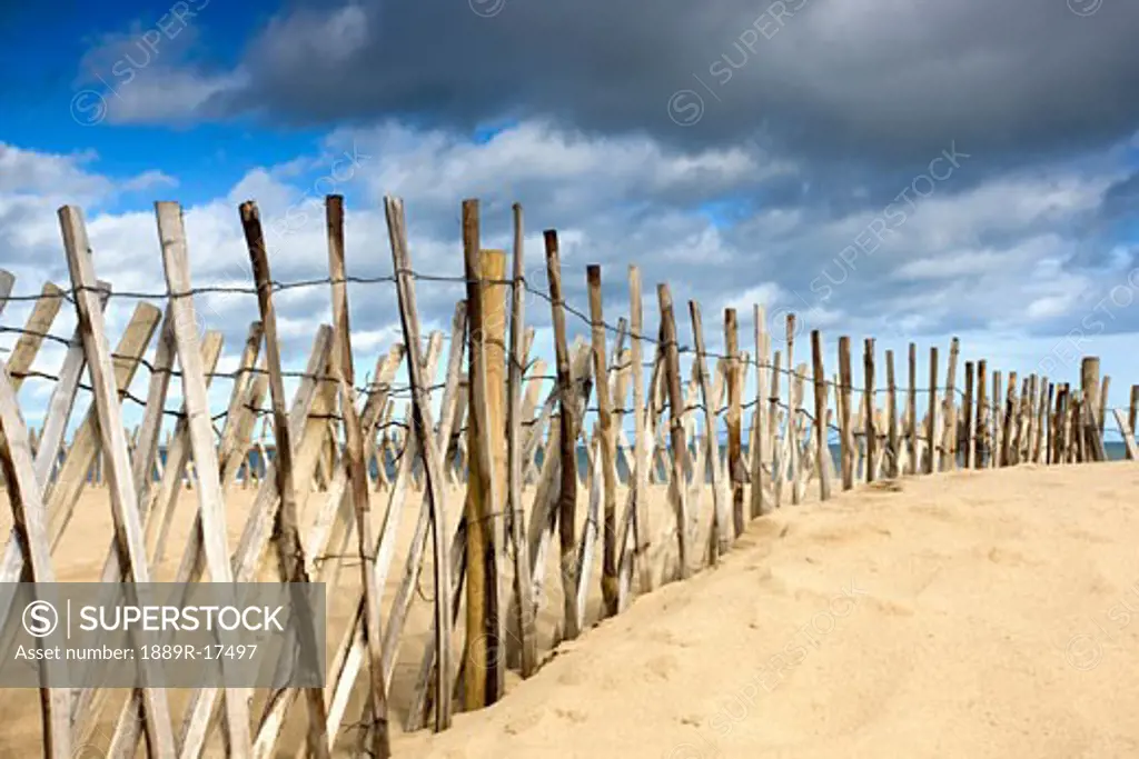 South Shields, Tyne and Wear, England; Dark clouds over fence on a beach