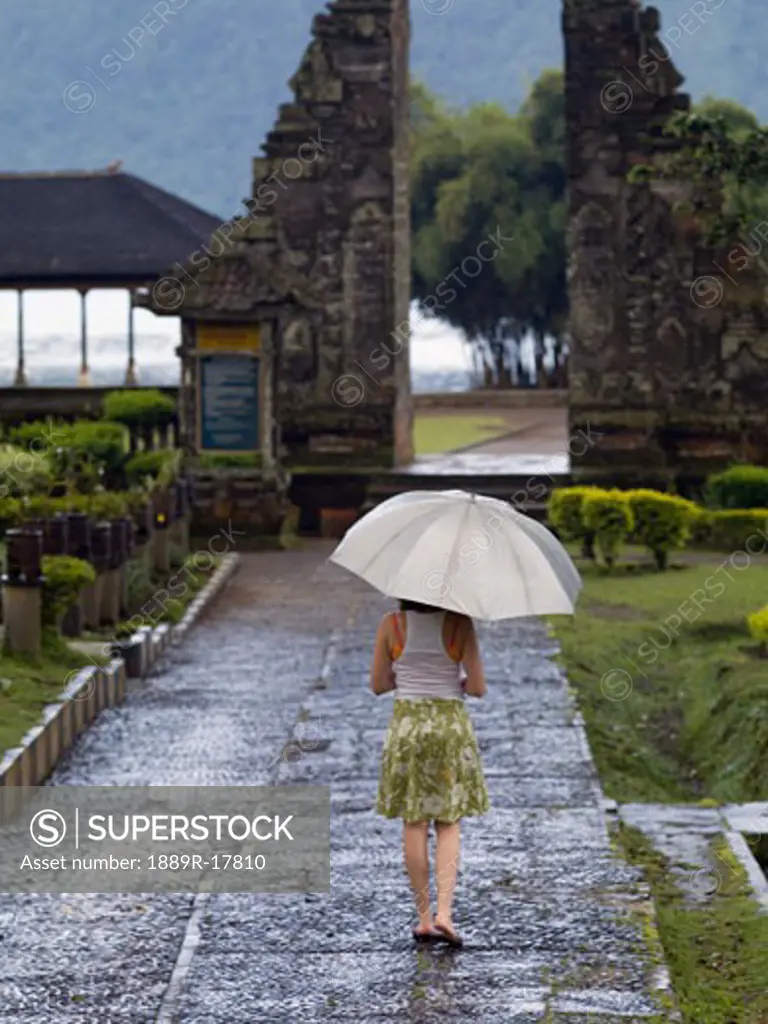 Ulun Danu Bratan Temple, Bali, Indonesia; Woman walking with umbrella