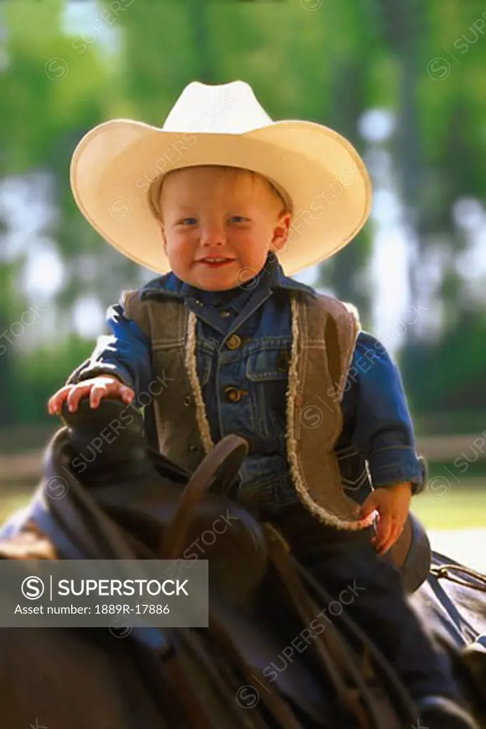 Toddler in western clothes sitting on a horse