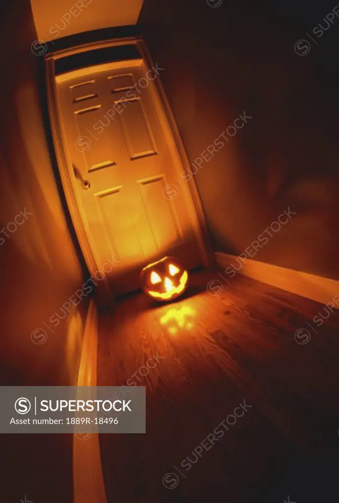 Lighted jack-o-lantern on floor in front of door