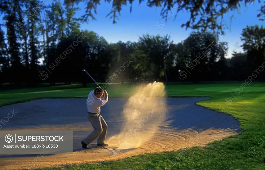 Golfer chipping out of sand trap