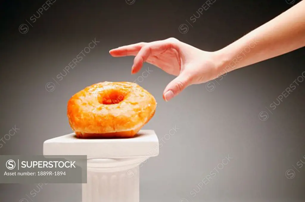 Someone taking a doughnut off a pillar