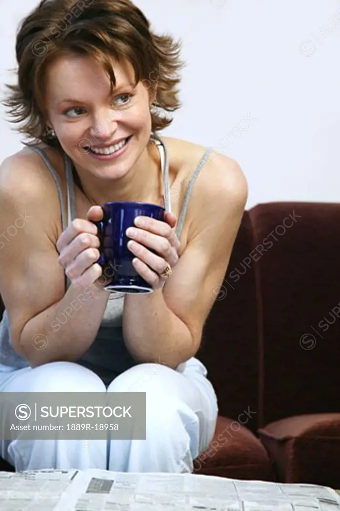 Woman drinking coffee in front of newspaper