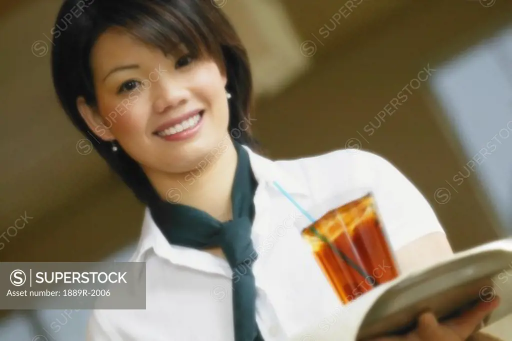Asian woman carrying drink on tray