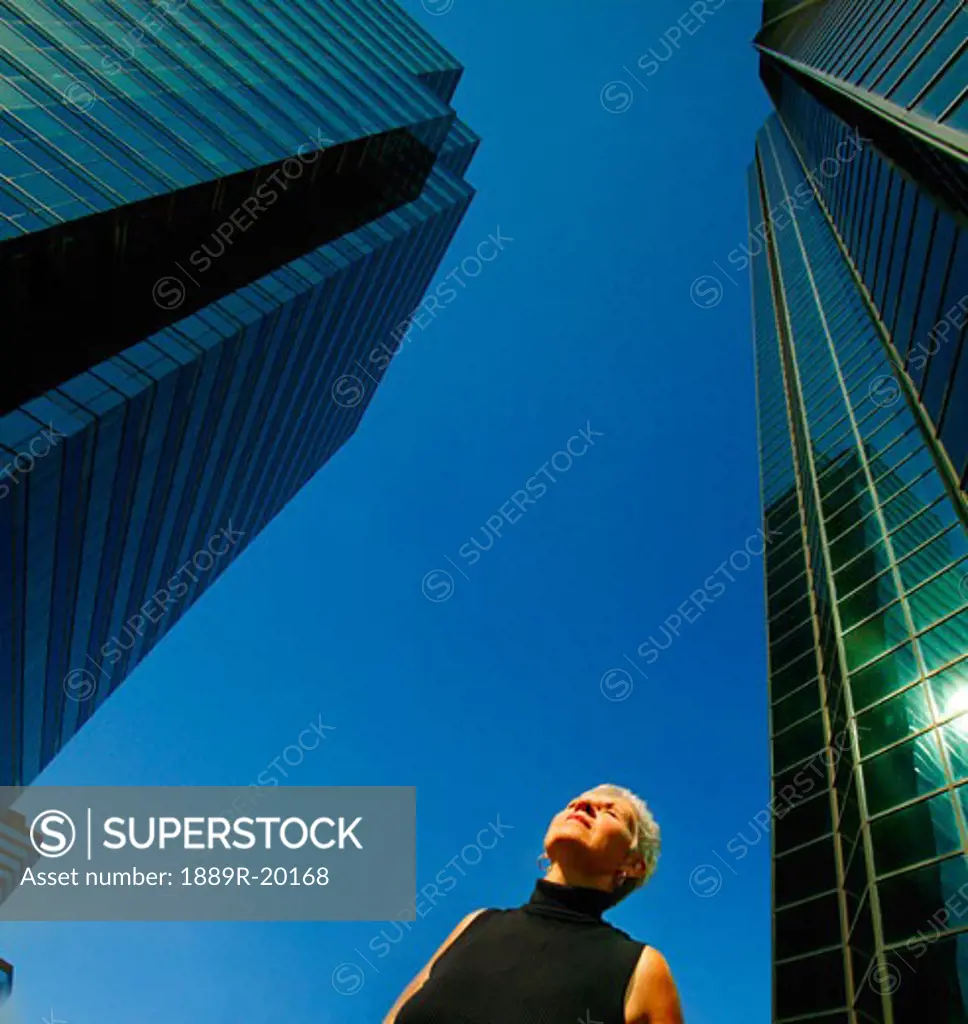 Woman stands by office towers