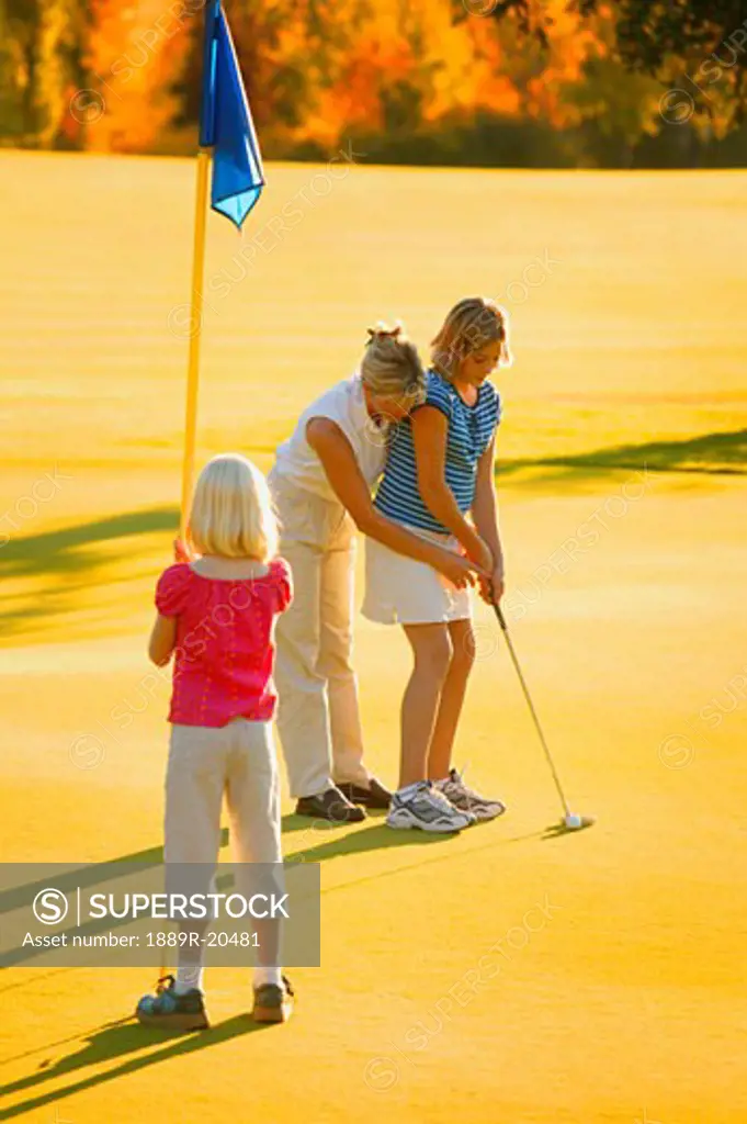 Mother shows daughter how to putt
