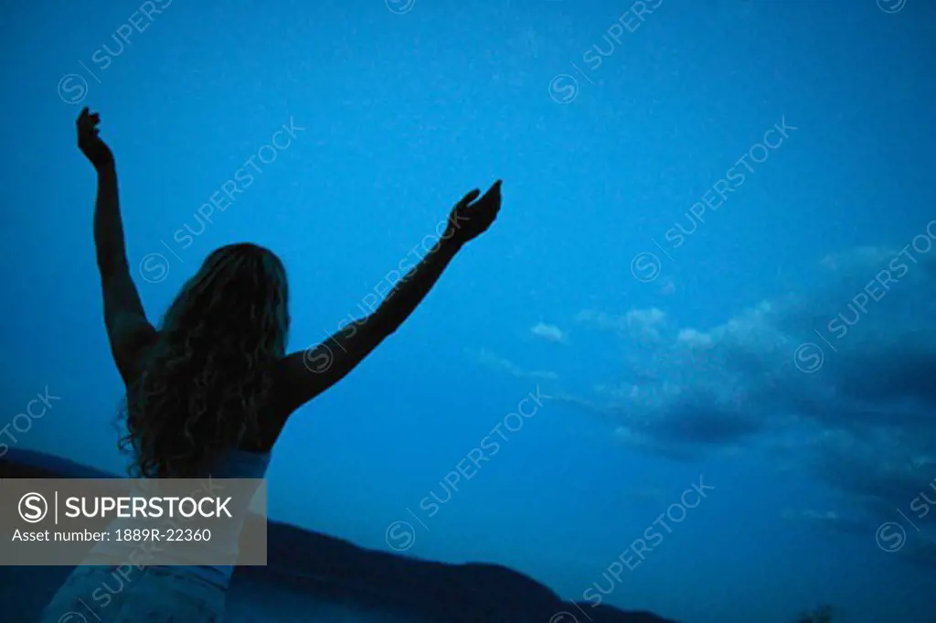 Woman lifts her hands toward heaven