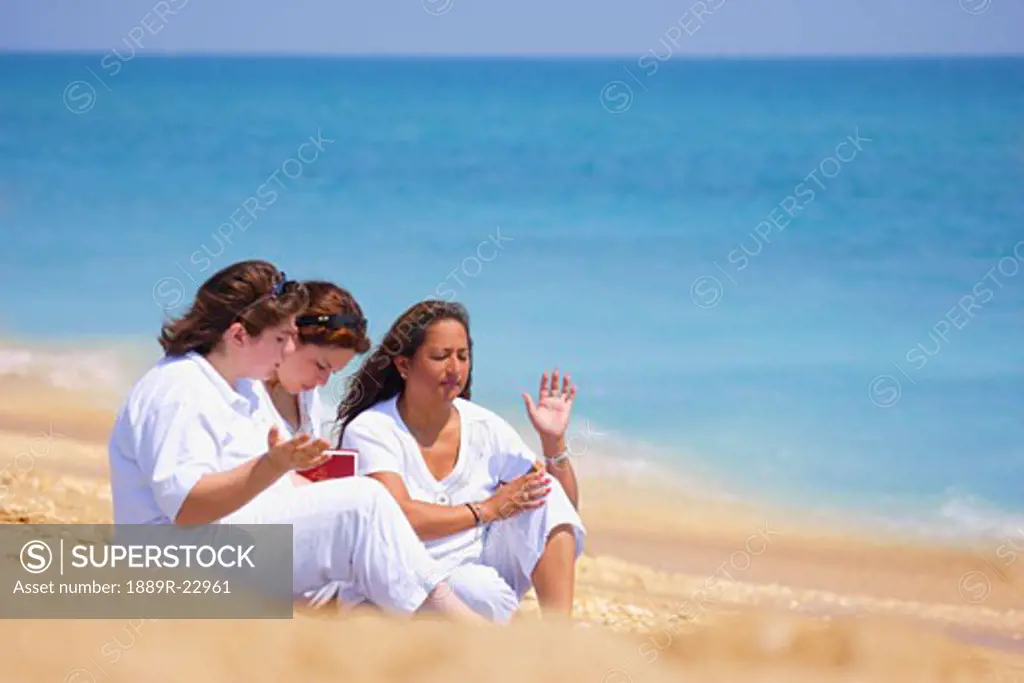 A group of women unite in prayer on the beach