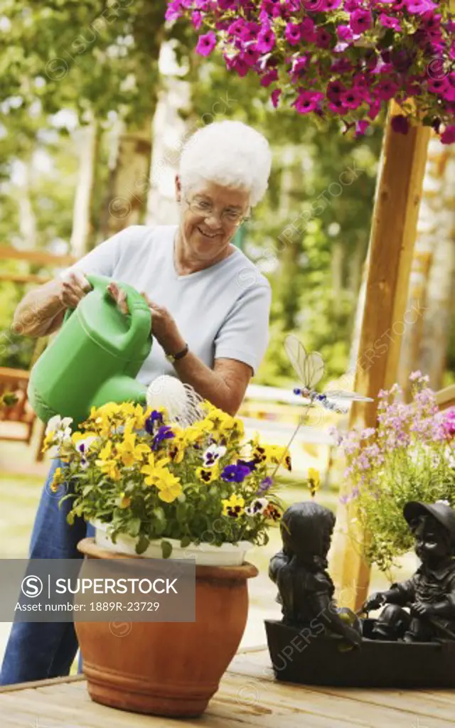 A senior woman waters a flower pot