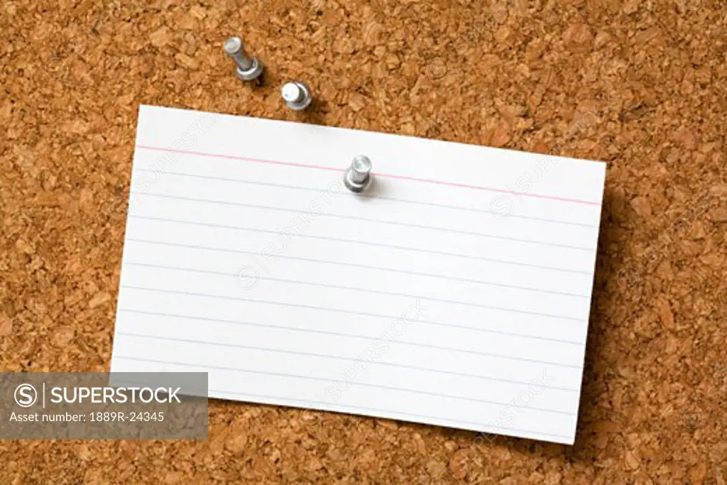 Note card and push pins on cork board