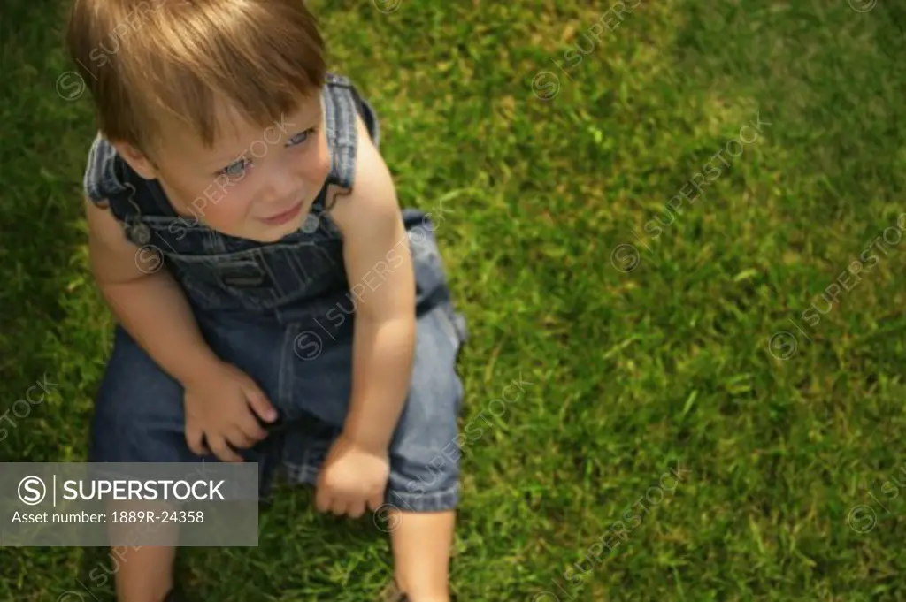Little boy sitting on grass