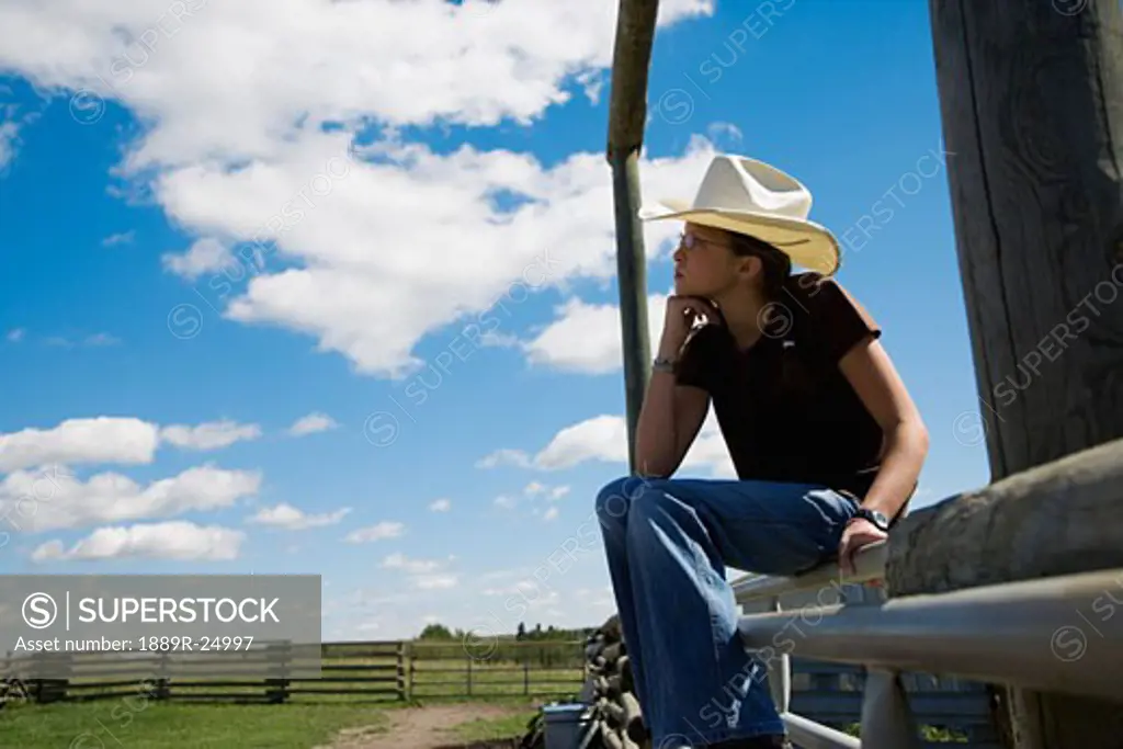 Cowgirl sitting on gate