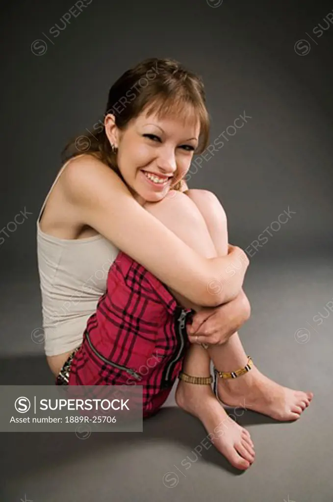 Woman sitting down hugging knees and smiling