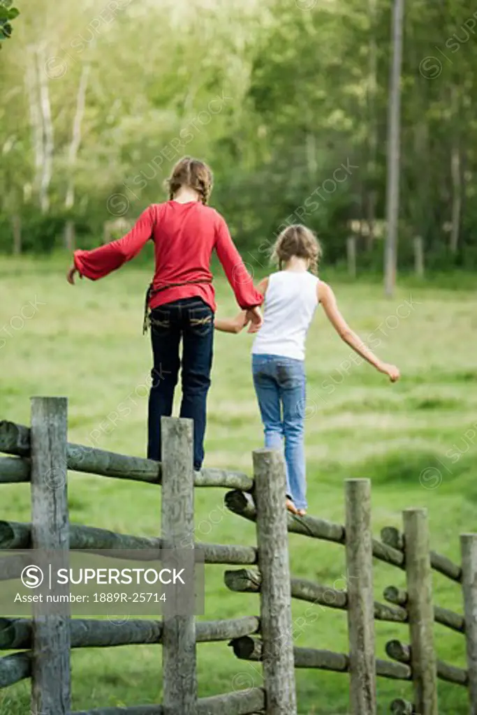 Girls walking on corral fence