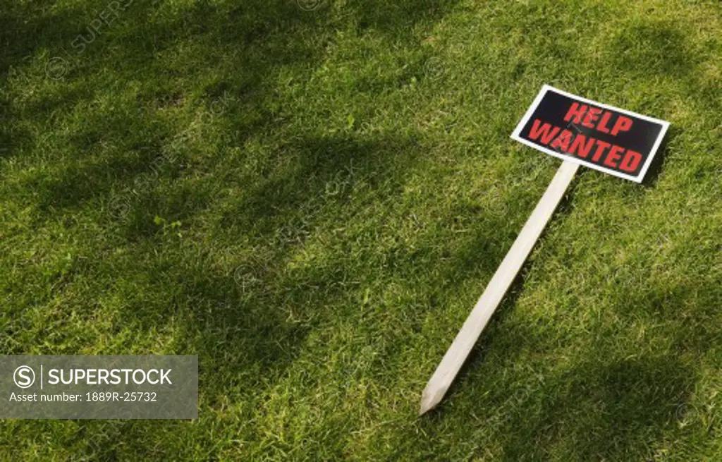 Help wanted sign laying on grass