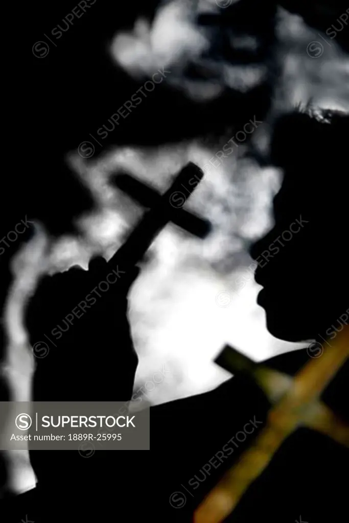 Silhouette of person holding cross