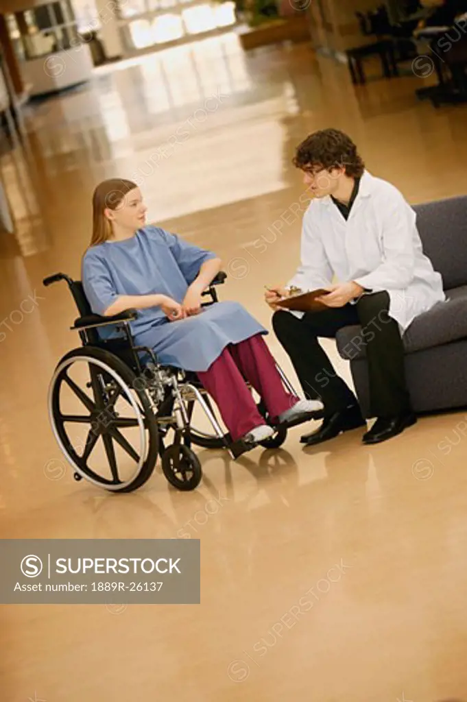 Young woman in wheelchair consulting with doctor
