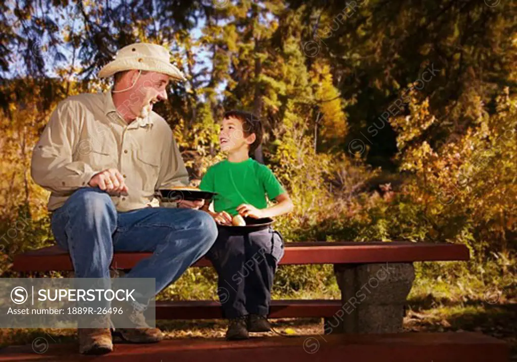 Father and son eating on a picnic table