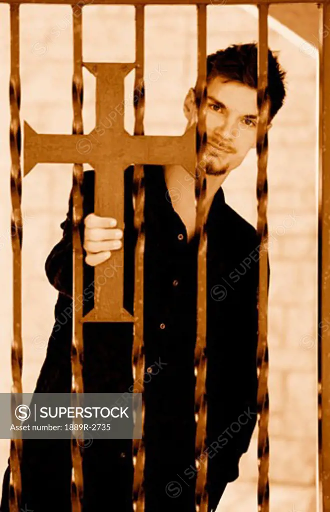 Man holding cross on iron fence