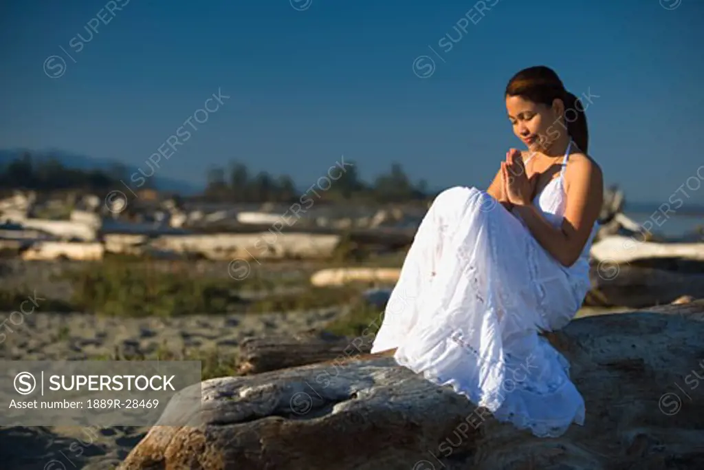 A young woman praying on the beach