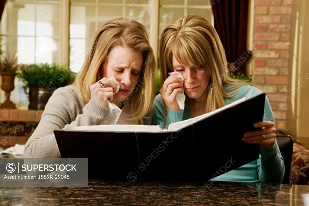 Women looking at a photo album and crying