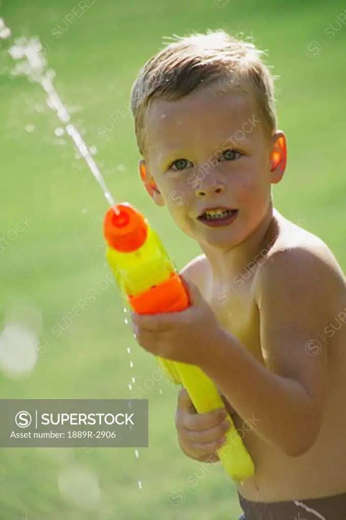 Little boy playing with a water shooter