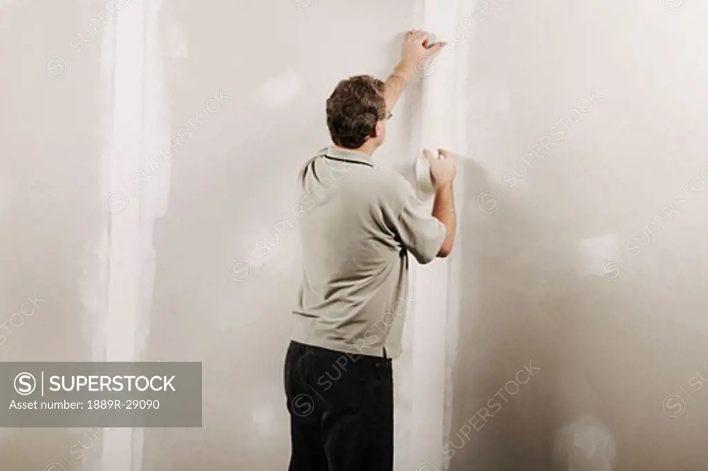 Man putting adhesive tape on a wall