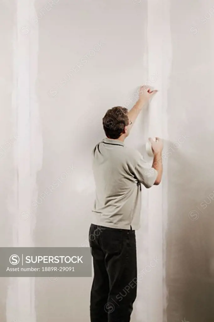 Man putting adhesive tape on a wall