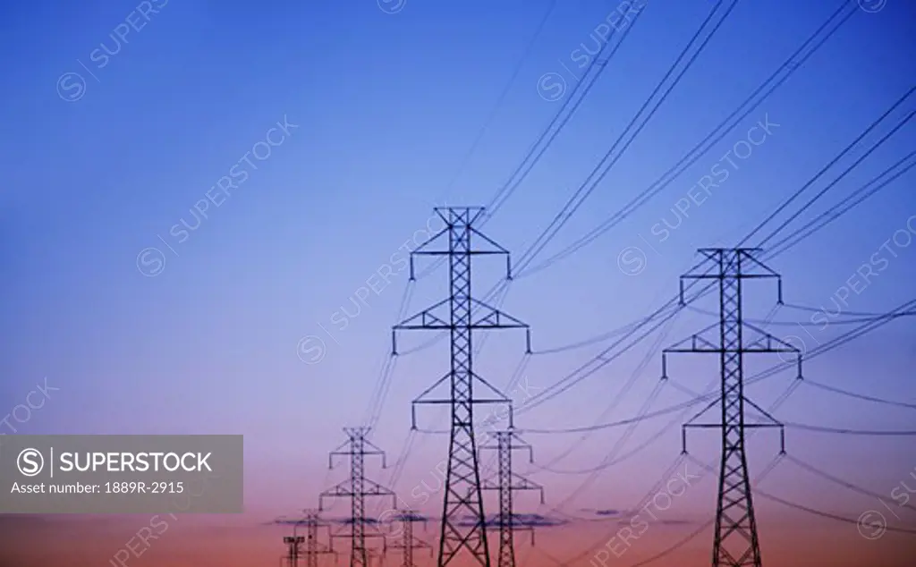 electricity pylons against a sunset backdrop