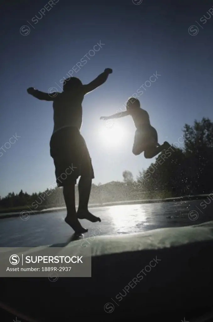 Two children jumping on a trampoline