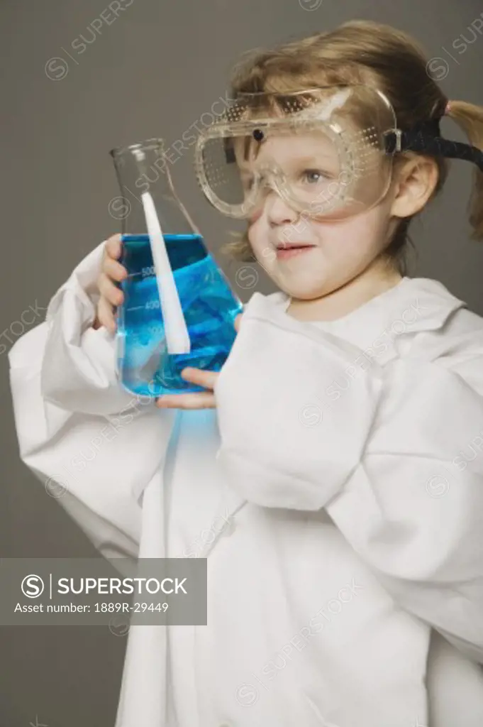 Little girl in safety glasses, holding beaker