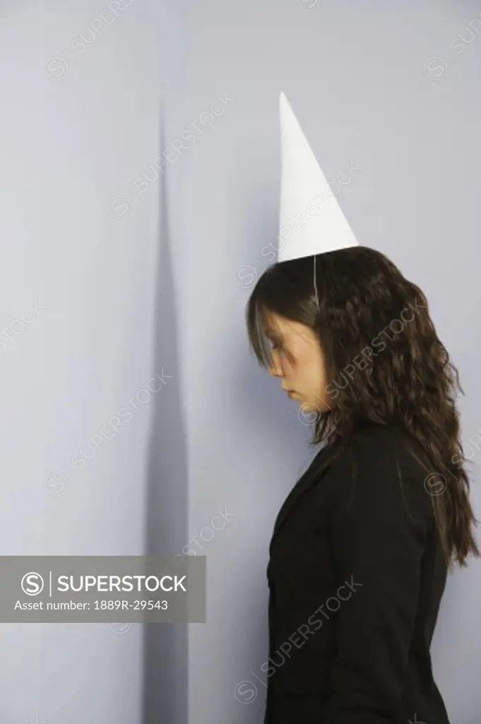 Woman facing corner with dunce cap