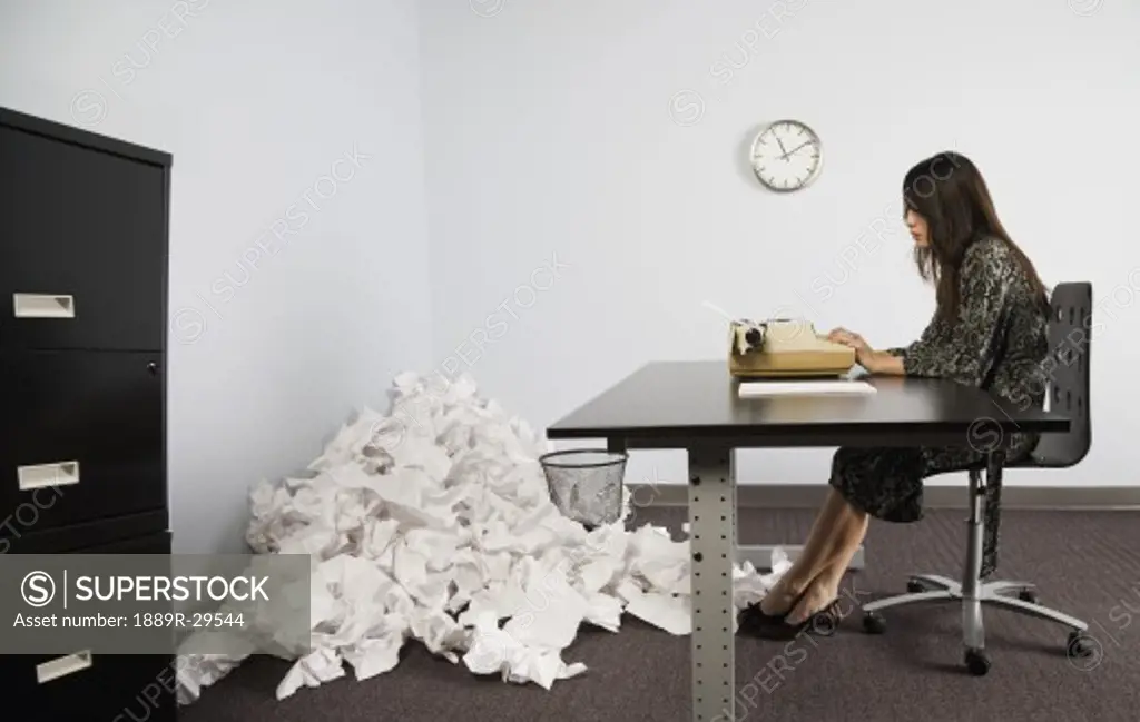 Businesswoman in office with crushed pile of paper on floor