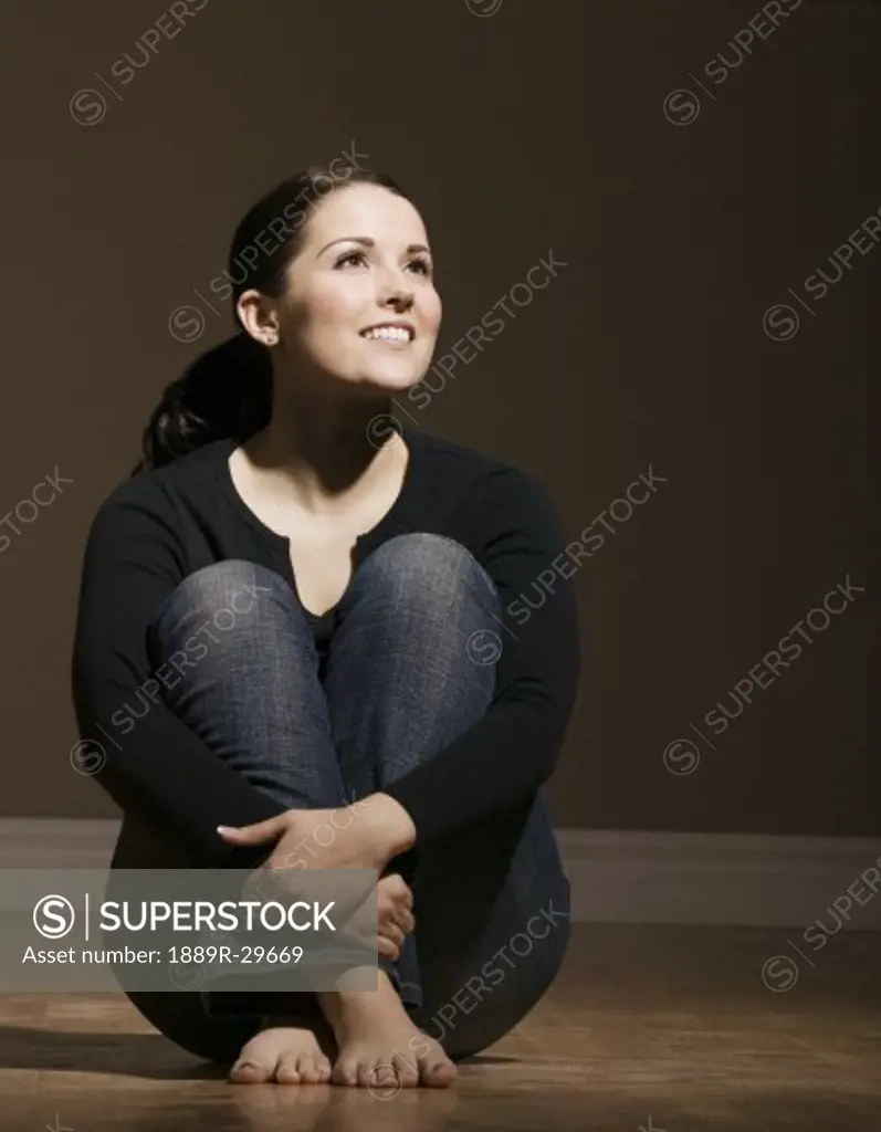 Smiling woman sitting and holding legs