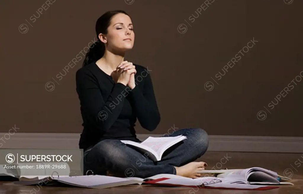Woman praying while studying on floor