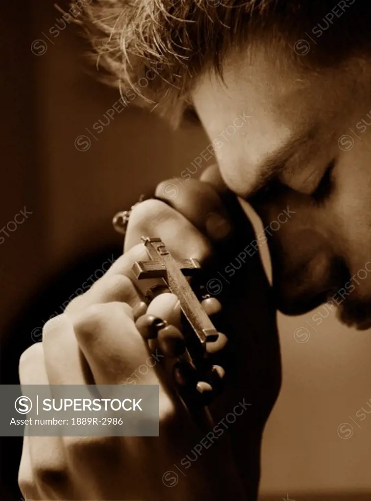 Man praying with cross in hands