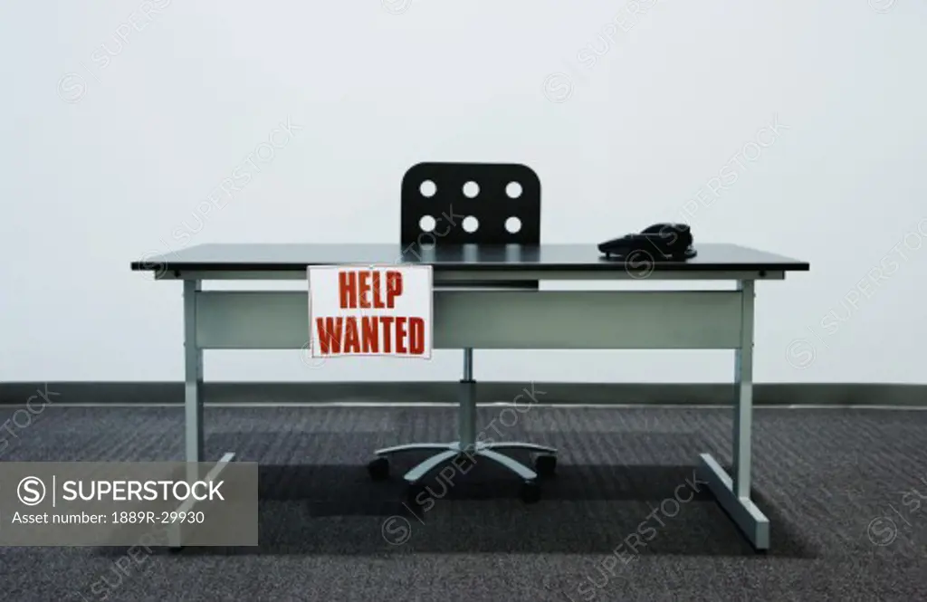 Empty desk with 'Help Wanted' sign