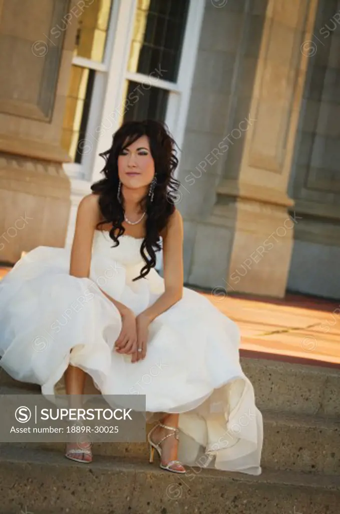 Bride sitting on outside steps in gown