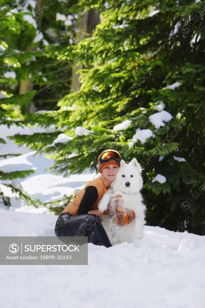Girl sitting with dog in snow