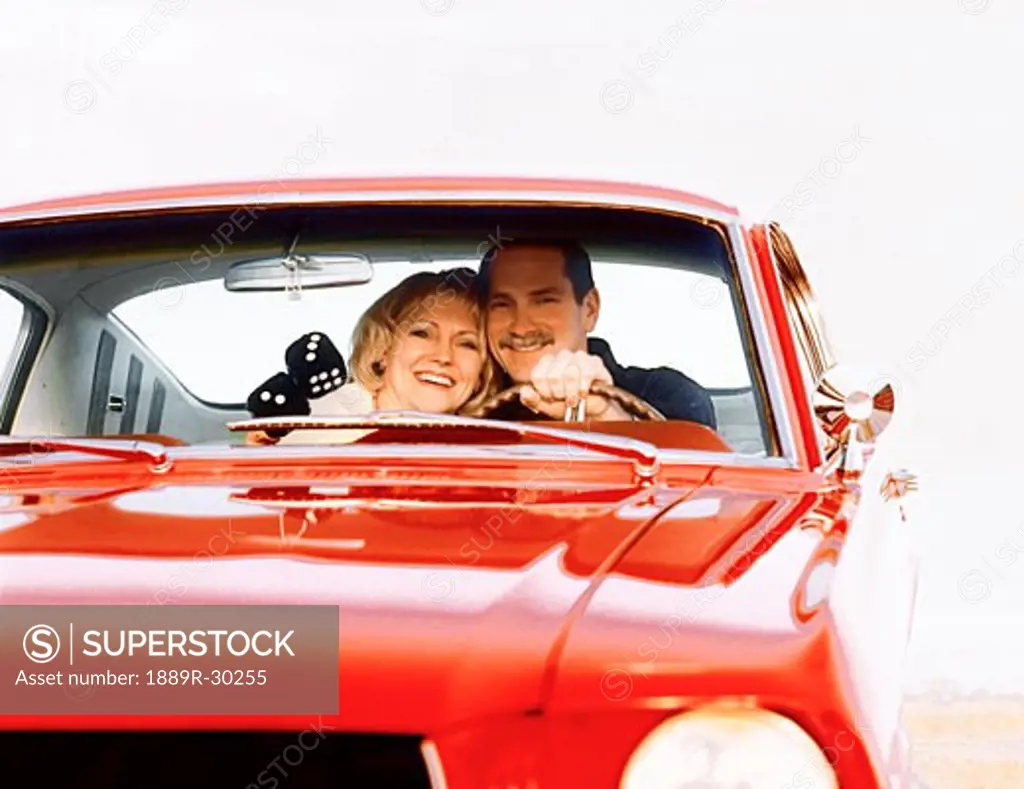 Middle aged couple in front seat of red car