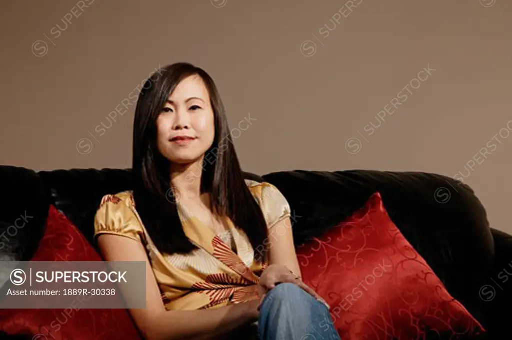 Middle aged asian woman sitting on couch