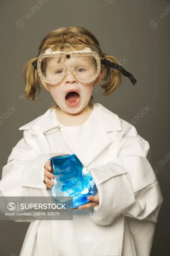 Little girl with safety goggles and lab coat holding a science beaker
