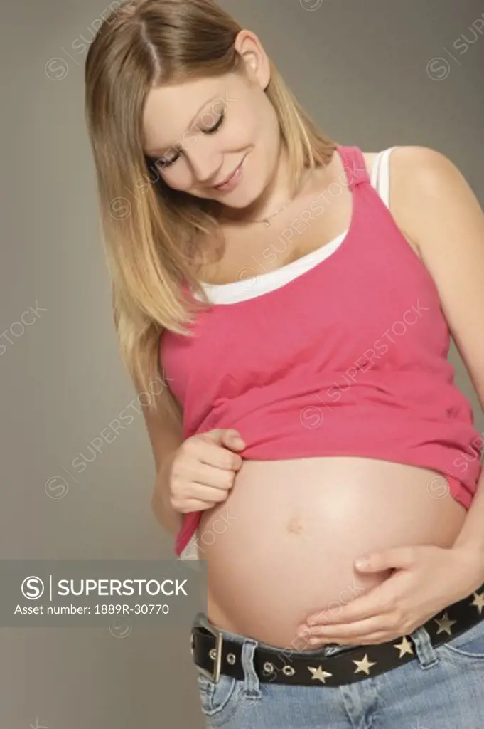 A pregnant woman looking at belly