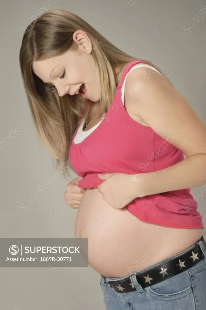 Side view of a pregnant woman looking at her belly